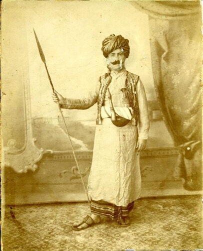 Homme en costume Ottoman traditionnel portant une lance sur un fond de studio de Photographe